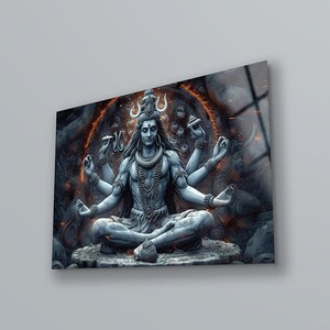 May include: A rectangular wall art print featuring a grey-toned depiction of a multi-armed deity sitting in a meditative pose. The figure is adorned with necklaces and a crescent moon symbol, set against a dark, textured background with glowing orange embers.