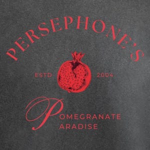 Puede incluir: Camiseta gris oscuro con un gráfico rojo. El gráfico incluye el texto "PERSEPHONE'S" arqueado sobre una ilustración de granada, con "ESTD 2004" a cada lado. Debajo, el texto dice "Pomegranate Paradise".