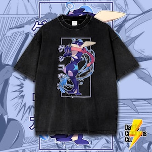 May include: Black t-shirt featuring a blue and white cartoon character wearing a blue hat and a blue scarf. The character is surrounded by blue water and the Japanese text "ゲッコウガ" is printed on the shirt.