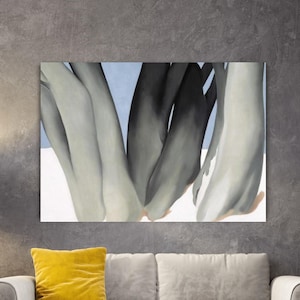 May include: Abstract art print featuring a close-up of intertwined limbs in shades of gray and black against a light blue and white background. The artwork is mounted on a wall above a sofa with a yellow pillow.