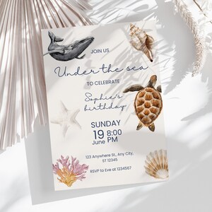 Puede incluir: Una invitación a una fiesta de cumpleaños con un tema de bajo el mar. La invitación presenta una ballena, una tortuga marina, una estrella de mar y conchas marinas. El texto de la invitación dice: "Únete a nosotros Bajo el mar para celebrar el cumpleaños de Sophie Domingo 19 8:00 Junio PM 123 Anywhere St, Any City, ST 12345 RSVP a Eve al 1234567".