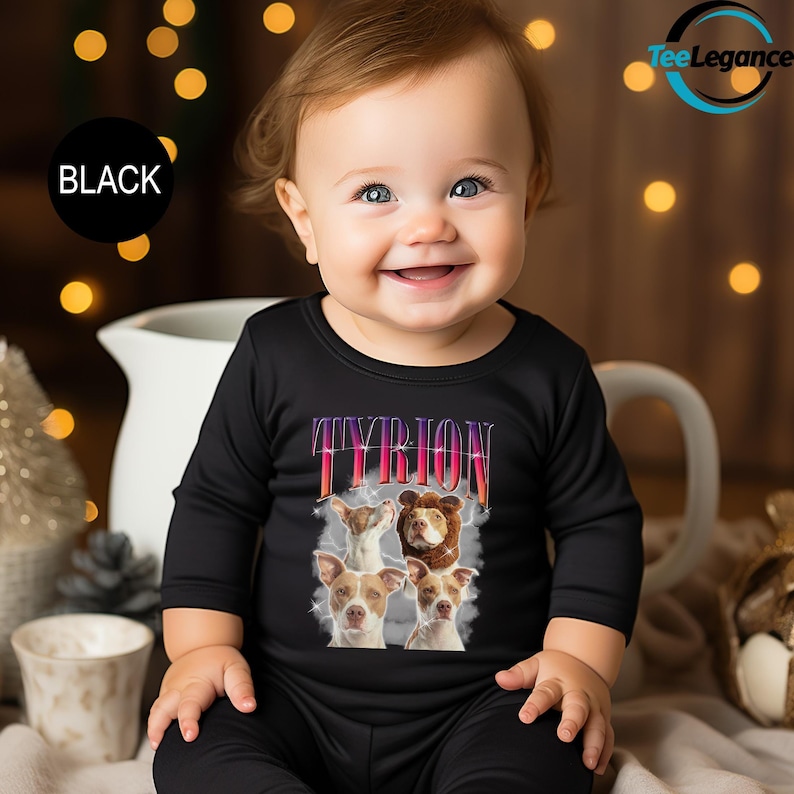 a baby sitting on a bed wearing a black t - shirt with a picture of