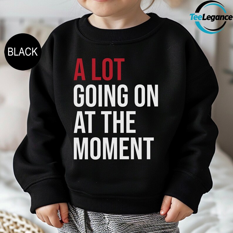 a little girl wearing a black sweatshirt that says a lot going on at the moment