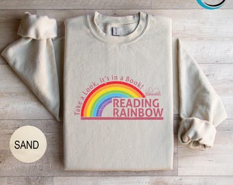 May include: A beige sweatshirt with a rainbow and the text "Take a look, it's in a book! Reading Rainbow" printed on the front.