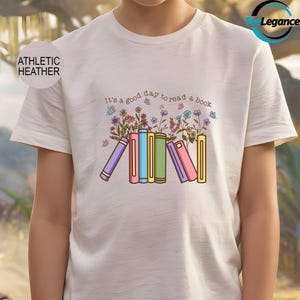 May include: White t-shirt with the text "It's a good day to read a book" in black. The text is surrounded by colorful flowers and a stack of colorful books.