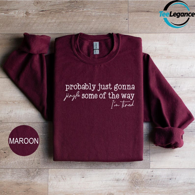 A maroon sweatshirt with the text "probably just gonna sing some of the way Tim I'm tired" printed on it, along with a small maroon circle with the text "MAROON" below it.