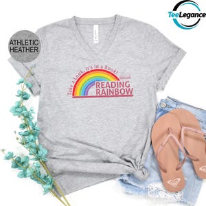 May include: A grey v-neck t-shirt with a rainbow and the text "Take a look, it's in a book! Reading Rainbow" printed on the front.