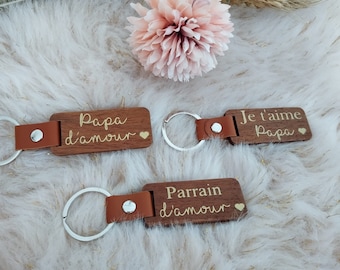 May include: Three wooden keychains with leather straps. The keychains have the text "Papa d'amour", "Je t'aime Papa" and "Parrain d'amour" engraved on them.