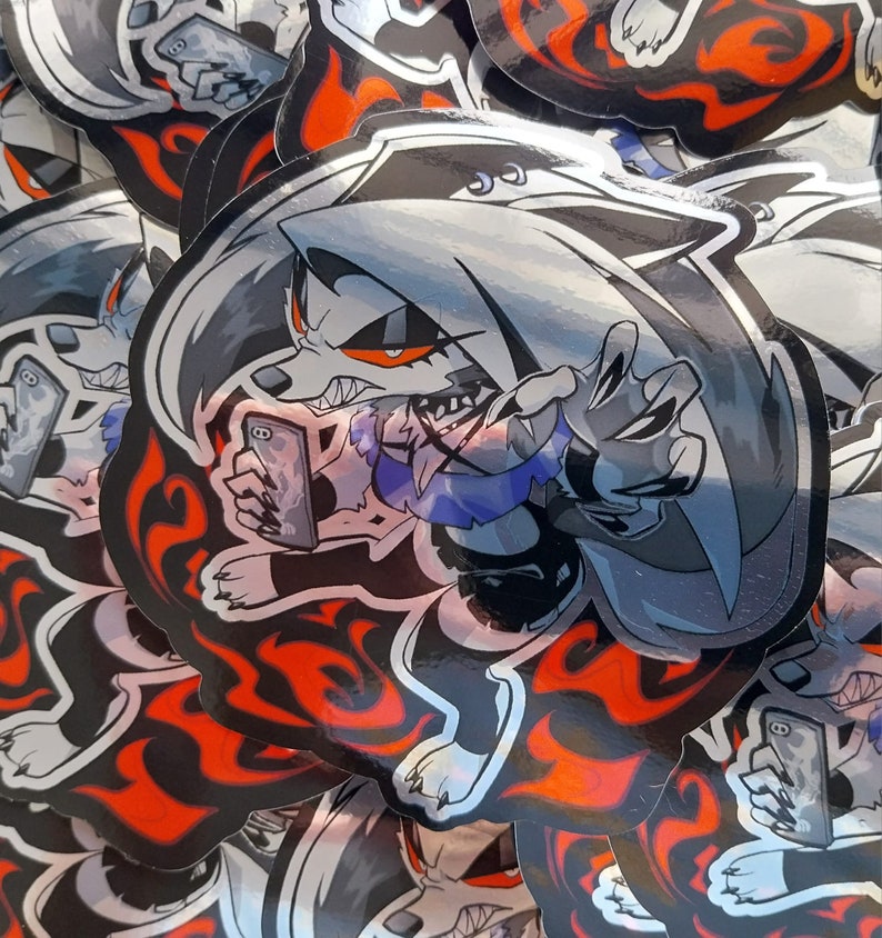 May include: A stack of stickers featuring a cartoon wolf character with red eyes, a black and white color scheme, and a red and black flame design. The wolf is holding a smartphone in its right paw and is making a gesture with its left paw.