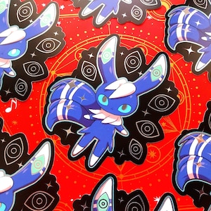 May include: A collection of die-cut stickers featuring a blue, rabbit-like creature with large teal eyes, white tufts of fur, and long ears marked with eye symbols. The character is set against a black background decorated with white eye icons.