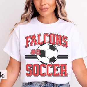 K&ouml;nnte beinhalten: Wei&szlig;es T-Shirt mit Fu&szlig;ballmotiv. Das Shirt zeigt das Wort "Falcons" in roten Blockbuchstaben &uuml;ber einer Fu&szlig;ballgrafik. Unter dem Ball ist das Wort "Soccer" in Rot gedruckt. Die Nummer "21" ist ebenfalls sichtbar.