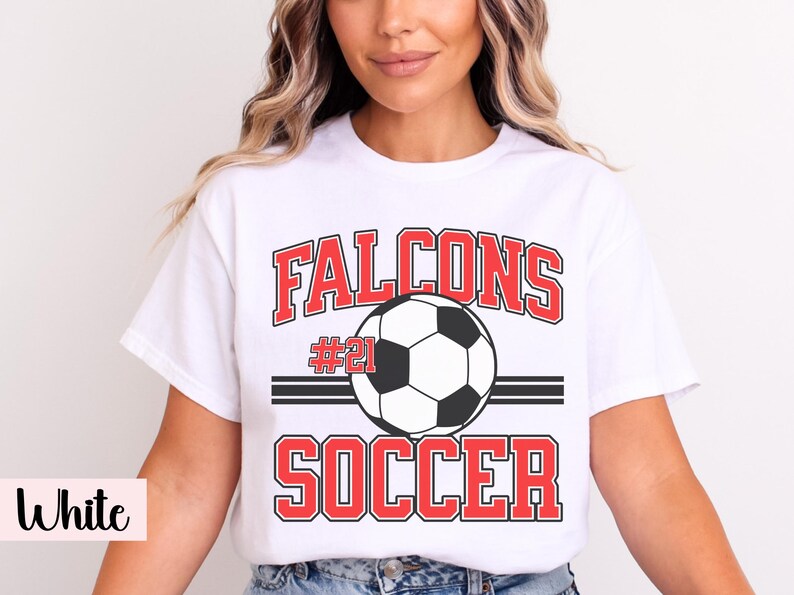K&ouml;nnte beinhalten: Wei&szlig;es T-Shirt mit Fu&szlig;ballmotiv. Das Shirt zeigt das Wort "Falcons" in roten Blockbuchstaben &uuml;ber einer Fu&szlig;ballgrafik. Unter dem Ball ist das Wort "Soccer" in Rot gedruckt. Die Nummer "21" ist ebenfalls sichtbar.