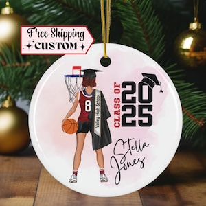 May include: A white ceramic ornament with a pink watercolor background. A basketball player wearing a red and white jersey with the number 8 is holding a basketball. The player is wearing a graduation cap and gown. The text "CLASS OF 2025" is in black and the text "Valley High School" is on a sash. The text "Stella Jones" is in pink.