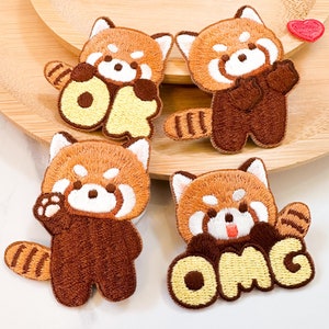 May include: Four embroidered iron-on patches featuring red pandas with the words "OK" and "OMG" in yellow lettering.