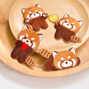 May include: Four embroidered iron-on patches featuring red pandas in various poses. The patches are brown, white, and red with detailed stitching.