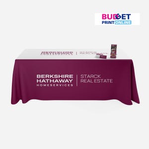 May include: A white and burgundy table cover with the text "Berkshire Hathaway Homeservices" and "Starck Real Estate" printed on it. The table cover is draped over a table with a stack of brochures on top.