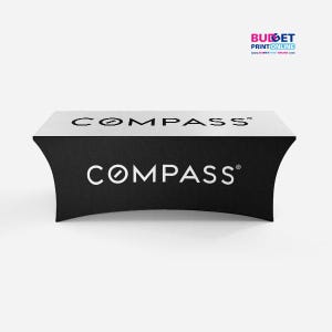 May include: Black and white table cover with the word "COMPASS" printed on it. The table cover is draped over a table.