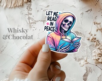 May include: A colorful sticker featuring a skeleton wearing a hoodie and holding a book. The text on the sticker reads "Let me read in peace."
