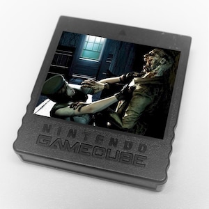 May include: A black Nintendo GameCube game cartridge with a graphic from a survival horror game. The image depicts a character in combat with a zombie in a dimly lit interior. The game's title is not visible.