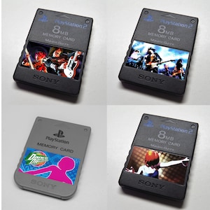 Peut inclure: Quatre cartes mémoire PlayStation 2. Trois sont noires avec des illustrations de jeux colorées, et une est grise avec un graphisme rose et vert. Chaque carte affiche le logo PlayStation 2, 8 Mo et la marque "SONY".