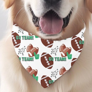May include: A golden retriever dog wearing a white bandana with a brown football and green "Go Team!" text pattern.