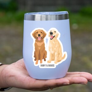 K&ouml;nnte beinhalten: Ein hellblauer Edelstahlbecher mit einem Aufkleber von zwei Golden Retriever Hunden, einer braun und einer cremefarben, die nebeneinander sitzen. Der Aufkleber lautet "Rudy & Bruce".