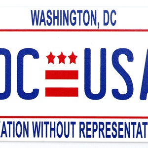 May include: A white sticker with blue and red text and stars. The text reads "DC USA" with "WASHINGTON, DC" at the top and "TAXATION WITHOUT REPRESENTATION" at the bottom.