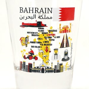 May include: A clear glass shot glass with a colorful illustration of a map of Bahrain. The map includes landmarks, cities, and the Bahraini flag. The text "BAHRAIN" and "مملكة البحرين" is printed on the glass.