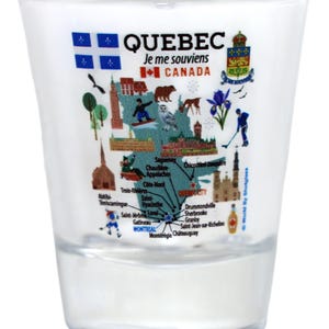 May include: Clear shot glass featuring a map of Quebec, Canada, with illustrations of landmarks and symbols. The glass has the text "QUEBEC Je me souviens CANADA" and is a souvenir item.