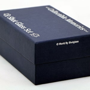May include: A navy blue box with the text "Shot Glass Set" and "Collectible Memories" printed in silver on the top. The bottom of the box has the text "World By Shotglass" printed in silver.