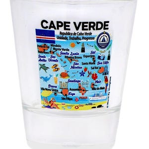 May include: Clear shot glass with a map of Cape Verde, featuring the country's flag and various locations. The text "CAPE VERDE" is printed at the top. The glass is cylindrical and transparent.