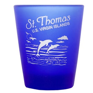May include: A blue shot glass with a white design of two dolphins jumping out of the water. The text "St. Thomas U.S. VIRGIN ISLANDS" is printed on the glass.