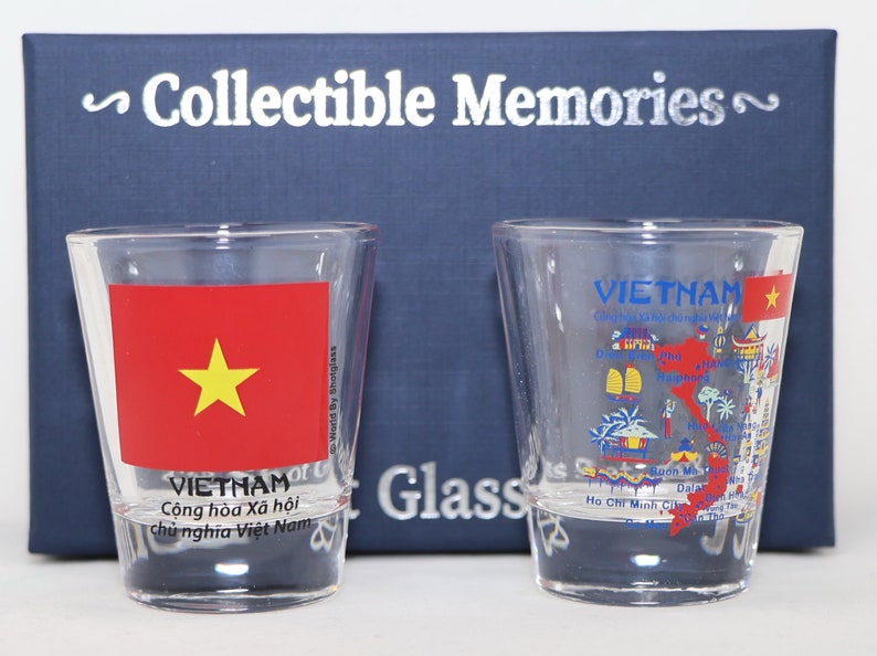 May include: Two clear glass shot glasses with a Vietnam theme. One glass features the Vietnamese flag with a red background and a yellow star. The other glass has a map of Vietnam with various landmarks and the text "VIETNAM" in blue.
