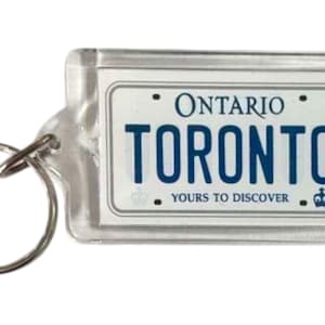 May include: Clear rectangular keychain featuring an Ontario license plate design. The plate reads "ONTARIO TORONTO YOURS TO DISCOVER" in blue and white. A silver key ring is attached to the keychain.