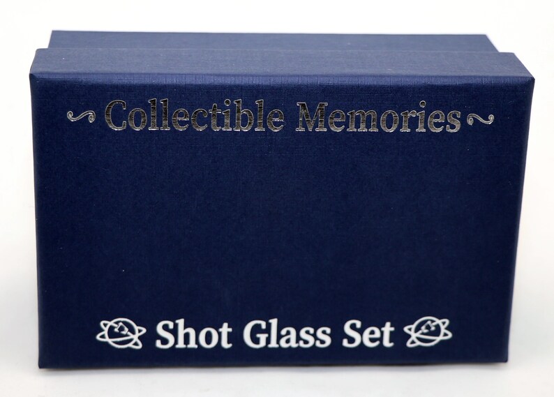 May include: A navy blue box with the text "Collectible Memories" and "Shot Glass Set" printed in silver and white.