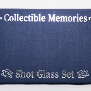 May include: A navy blue box with the text "~Collectible Memories~" and "Shot Glass Set" printed in silver. The box has a textured surface and a silver design on each side.