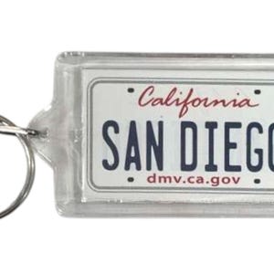 Op de afbeelding: Transparante rechthoekige sleutelhanger met een ontwerp van een Californische nummerplaat. De plaat leest "SAN DIEGO" in marineblauwe letters, met "California" in rood script erboven.