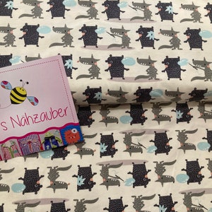 Könnte beinhalten: Weißer Stoff mit einem sich wiederholenden Muster aus schwarzen und grauen Cartoon-Wölfen, die Blasen pusten. Der Stoff hat den Text "Bine's Nähzauber" aufgedruckt.