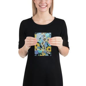 Puede incluir: Una impresión colorida con una serpiente amarilla y blanca serpenteando a través de un campo de flores azules y amarillas sobre un fondo negro.