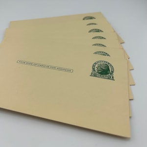 May include: A stack of vintage postcards with a cream-colored background. Each postcard has a green postage stamp with a portrait and the text "THIS SIDE OF CARD IS FOR ADDRESS".