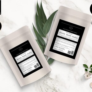 May include: Two off-white pouches of body bath salts with black labels. The labels read "Body Bath Salts" and include product information. The image also includes text that says "Editable in Canva", "Bonus Items Inside", and "Instant Download".