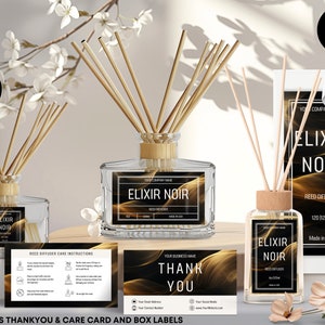 Könnte beinhalten: Mockup eines Etiketts für eine Reed-Diffuser-Flasche mit gold-schwarzem Design. Das Etikett lautet "Elixir Noir" und "Reed Diffuser". Die Flasche ist aus klarem Glas mit einem Holzdeckel und braunen Schilfrohren. Der Mockup enthält eine Dankeskarte und eine Pflegehinweiskarte.