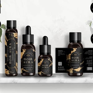 Könnte beinhalten: Vier Flaschen mit ätherischem Öl mit schwarzen und goldenen Etiketten. Die Etiketten zeigen ein Marmormuster und den Text "Noir Aura Essential Oil" mit den Worten "Chamomile & Acai" darunter. Die Flaschen sind auf einem weißen Regal angeordnet.