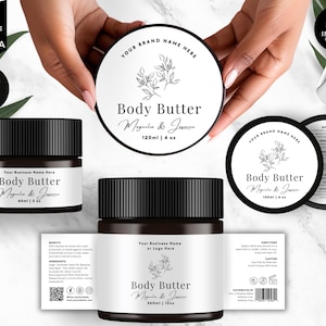 May include: A collection of body butter jars and labels with a minimalist design. The labels feature the text "Body Butter Magnolia & Jasmine" and include a floral illustration. The jars are black with white labels, and the product sizes are 2 oz, 4 oz, and 12 oz.