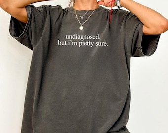 May include: A dark gray oversized t-shirt with the text "undiagnosed. but i'm pretty sure." printed in white.