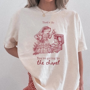 May include: A white ceramic mug with a black handle and the text "But First, Coffee" in a black, bold font. The mug is sitting on a white surface. The mug is approximately 4 inches tall.