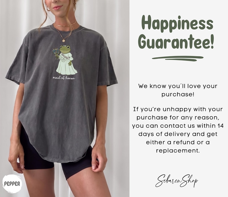 K&ouml;nnte beinhalten: Ein anthrazitfarbenes Kurzarm-T-Shirt mit einer Grafik eines Frosches in einem wei&szlig;en Kleid, der einen Blumenstrau&szlig; h&auml;lt, darunter der Text "maid of honor". Rechts steht der Text "Happiness Guarantee!" sowie Details zur R&uuml;ckgaberichtlinie.