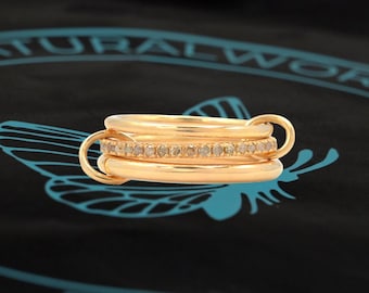 Könnte beinhalten: Drei goldene Ringe mit einer Reihe kleiner Diamanten am mittleren Ring.
