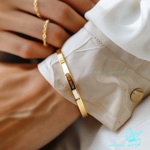 Puede incluir: Pulsera de brazalete de oro con la inscripción "Cree en ti mismo" grabada en el exterior.