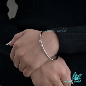 May include: A silver bangle bracelet with a single clear rhinestone on the side.